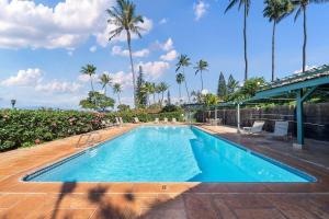 a large swimming pool with palm trees in the background at International Colony Club 37 · ICC 37 Remodeled Hawaiian Cottage in Kaanapali