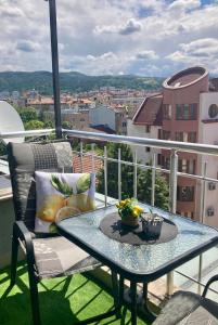 a table on a balcony with a view of a city at Cozy apartment Alba with two bedrooms! in Blagoevgrad