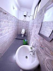 een badkamer met een wastafel en een spiegel en een toilet bij Sleeping Buddha Homestay - Lamahatta in Darjeeling