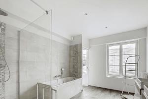 a white bathroom with a tub and a glass shower at Stunning 230m with garden in the city center in Caen