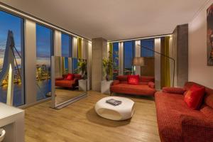 a living room with red furniture and large windows at nhow Rotterdam in Rotterdam