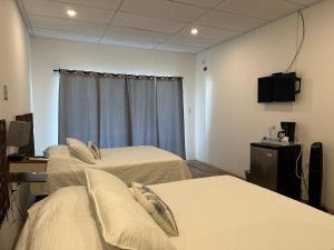 a room with three beds and a flat screen tv at Lali Beach Hotel Boutique in Sonsonate