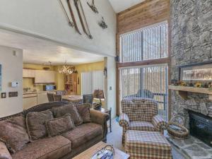 a living room with a couch and a stone fireplace at 2-Level Swiss Mountain Condo Seven Springs in Champion
