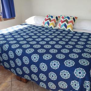 a bed with a blue and white quilt on it at Casitas Las Palmas - Coral de Mar in Punta Mita