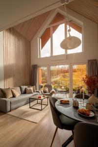 een woonkamer met een bank en een tafel bij Hill & Chill Kudowa Zdrój - nowoczesne stodoły ze strefą SPA, balia, sauna in Kudowa-Zdrój +45 foto's