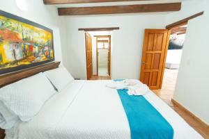 a bedroom with a white bed with a painting on the wall at Apartamento Madeiro in Villa de Leyva