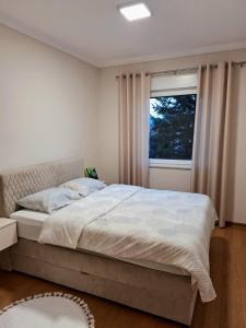 a bedroom with a large bed with a window at Apartman REINA in Prijedor