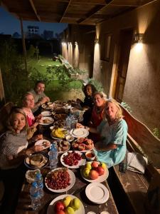 a group of people sitting around a table with food at Sahure Pyramid View Inn in Cairo