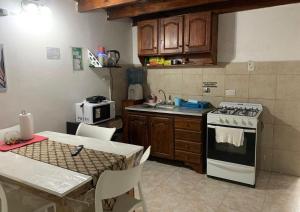 a kitchen with a stove and a sink and a table at Disfrutá tu estadía en Romana Dolores a solo 10 cuadras del parque termal Conseguí un ahorro exclusivo para el parque in Dolores