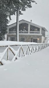 ein schneebedecktes Haus vor einem Zaun in der Unterkunft Chalet del Lago Laceno in Laceno