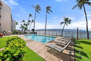 a swimming pool with chairs and a view of the water at Lauloa 403 · LOA 403 Fully Remodeled Direct Oceanfront 2BD in Wailuku