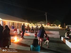 a group of people standing around a fire at night at Rann Rajvi Homestay in Dhordo