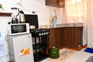 a small kitchen with a microwave and a refrigerator at Luxe-homestay 1 Bed Executive Studio in Eldoret +6 photos