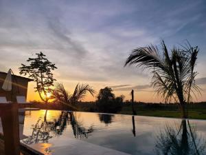 a sunset over a swimming pool with a palm tree at Villa Đăng Hải in Buôn Du Enguôl