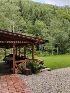 un pavillon en bois dans un parc avec un champ et des arbres dans l'établissement Cabana de la râu! Ciubăr aero hidro masaj, à Măguri-Răcătău