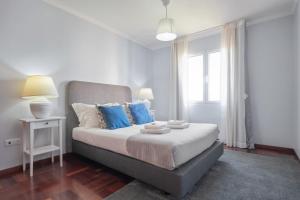 a bedroom with a bed with blue pillows and a window at Piornais by Homie in Panasqueira