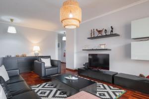 a living room with black furniture and a flat screen tv at Piornais by Homie in Panasqueira