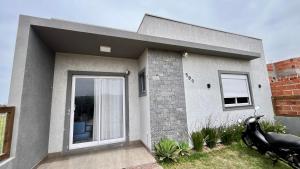 a house with a motorcycle parked in front of it at Casa pertinho do mar in Capão da Canoa