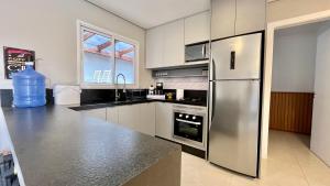a kitchen with a stainless steel refrigerator and a window at Casa pertinho do mar in Capão da Canoa