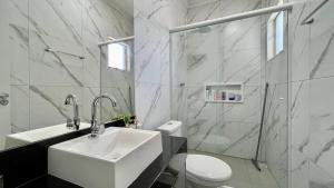 a white bathroom with a sink and a toilet at Casa pertinho do mar in Capão da Canoa +15 photos