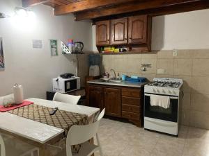 a kitchen with a stove and a sink and a table at Disfrutá tu estadía en Romana Dolores a solo 10 cuadras del parque termal Conseguí un ahorro exclusivo para el parque in Dolores