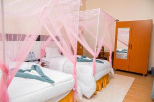 - 2 lits dans une chambre avec des moustiquaires roses dans l'établissement CASA BETANIA Musanze Karwasa, à Gasanze