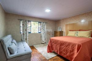 um quarto com uma cama, uma cadeira e uma janela em Casa com Wi-Fi e garagem a 400m do Museu Imperial em Petrópolis