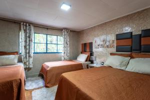 um quarto de hotel com duas camas e uma janela em Casa com Wi-Fi e garagem a 400m do Museu Imperial em Petrópolis