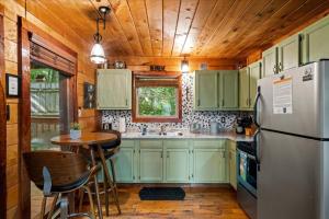 a kitchen with green cabinets and a table and a refrigerator at Hot Tub & WiFi - Romantic Hideaway in Slade