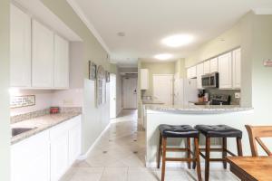 une cuisine avec des armoires blanches et des tabourets de bar dans l'établissement Beachview Condo in Legacy Tower1 -303 - with Reserved Parking Spot in front, à De Buys