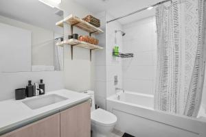 een witte badkamer met een wastafel, een toilet en een bad bij Downtown Calgary Modern 1BR with Pullout couch in Calgary +18 foto's