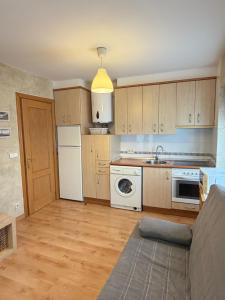 Una cocina con gabinetes de madera y un refrigerador blanco. en Casa del Plantel, en La Granja de San Ildefonso