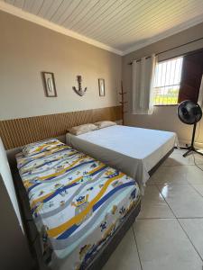 a bedroom with a bed with a comforter on it at Casa Duplex praia de Ubu in Anchieta +3 photos