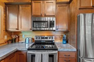 a kitchen with stainless steel appliances and wooden cabinets at Hot Tub & WiFi - Sky Pointe - LUX cabin in RRG KY in Rogers +56 photos