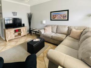 a living room with a couch and a flat screen tv at 146 Beau Clair - Beachside Townhome with Pool in Long Beach in Long Beach