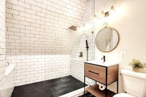 a white bathroom with a sink and a mirror at The Black Aframe - HOT TUB and Mountain Views in Evergreen Farms