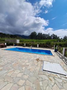 an image of a swimming pool with a stone patio at Chalés Quintal da Serra in Lavrinhas