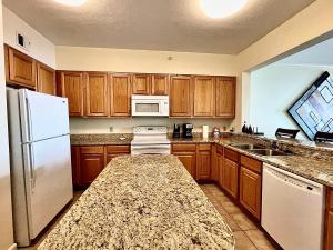 une cuisine avec des armoires en bois et un réfrigérateur blanc dans l'établissement Beachview Condo in Legacy Tower 1-1004 - fully furnished 3 bedroom 2 bathroom, à De Buys