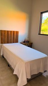 a bedroom with a large white bed with a window at Chalés Quintal da Serra in Lavrinhas