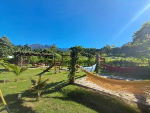 a hammock in a park with mountains in the background at Chalés Quintal da Serra in Lavrinhas