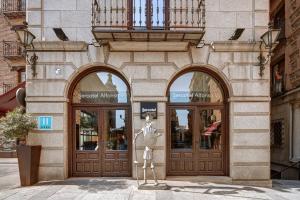 a building with two doors and a statue in front of it at Hotel Sercotel Alfonso VI in Toledo
