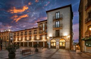 a building in a city with a sunset at Hotel Sercotel Alfonso VI in Toledo