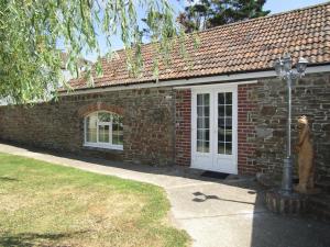 a brick house with a statue in front of it at Charming Barn - 2 Bed in Westward Ho
