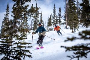 two people are skiing down a snow covered slope at Shorehouse Hotel in Buena Vista