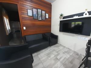 瓜拉图巴Casa Colonial em Guaratuba, próximo a praia的房间里有一台平板电视和一张黑色沙发。