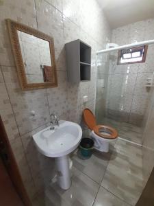 瓜拉图巴Casa Colonial em Guaratuba, próximo a praia的浴室里有洗手池、马桶和镜子。 更多25张照片