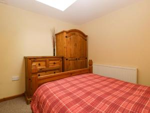 a bedroom with a bed and a wooden cabinet at Dovecote Cottage in Gloucester