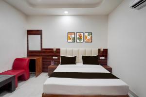 a bedroom with a bed and a red chair at HOTEL O THE ELEGANT in Anūpnagar