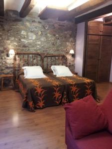 a bedroom with two beds and a stone wall at Casa Rafeleta Hotel in Plan