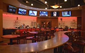 um restaurante com mesas e cadeiras e televisões na parede em The Clarion Hotel Philadelphia Airport em Essington